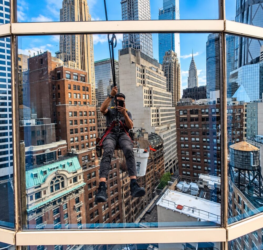 Rope access window replacement on the Sofitel tower with the Chrysler Building in view